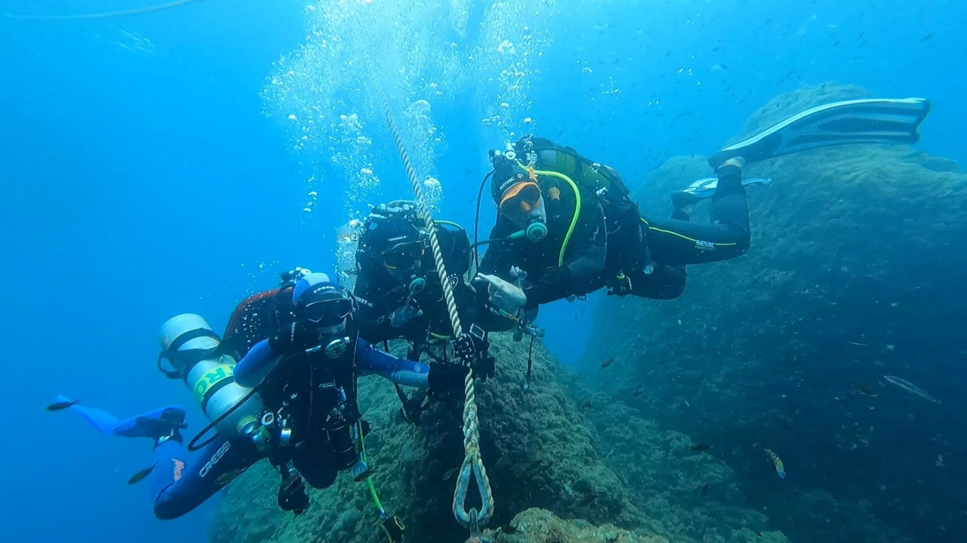 Trois plongeurs en exploration le long du mouillage sur un tombant méditerranéen